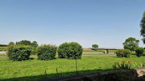 Jardin luxuriant avec topiaires et vue sur la rivière à l'Hôtel Rose, Beauvoir