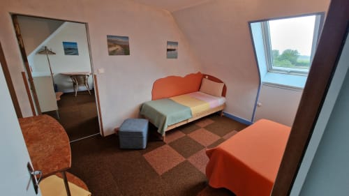 Chambre lumineuse à l'Hôtel Rose Beauvoir avec canapé orange, vue sur la rivière et carrelage marron
