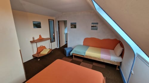 Chambre communicante douillette à l'Hôtel Rose à Beauvoir avec lits colorés, mobilier orange et vue sur la rivière par les lucarnes.