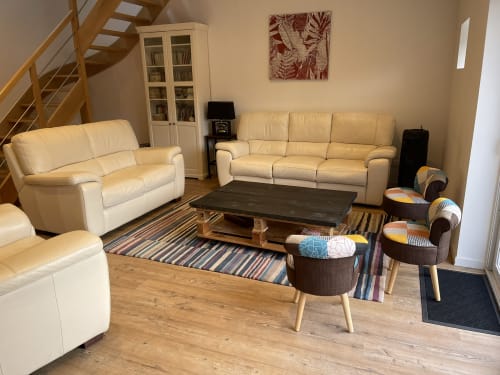 Salon moderne avec canapés en cuir crème, table basse noire et tapis rayé aux Gites De Flaubert au Heron, France.