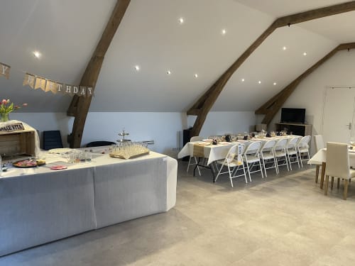 Spacious event venue at Les Gites De Flaubert with decorated tables, beamed ceilings, and birthday banner
