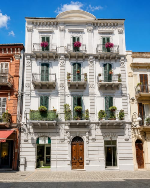 Edificio storico neoclassico bianco a Ortona con balconate ornamentali e fiori rosa, facciata di Trabocchi Livings