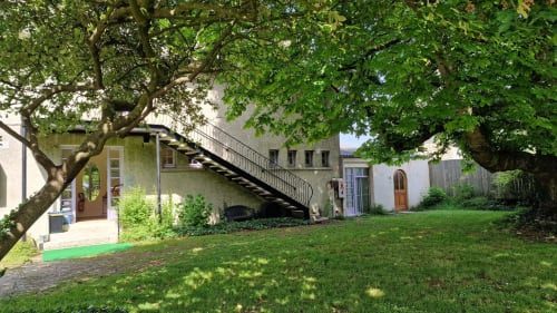 Jardin verdoyant de l'Hôtel Rose à Beauvoir avec arbres matures, pelouse et entrée accessible