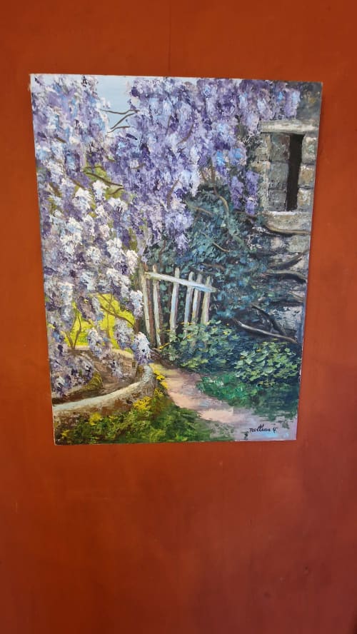 Des fleurs de glycine violette encadrent une ancienne arche de pierre avec un portail usé et du lierre luxuriant à l'Hôtel Rose à Beauvoir, France