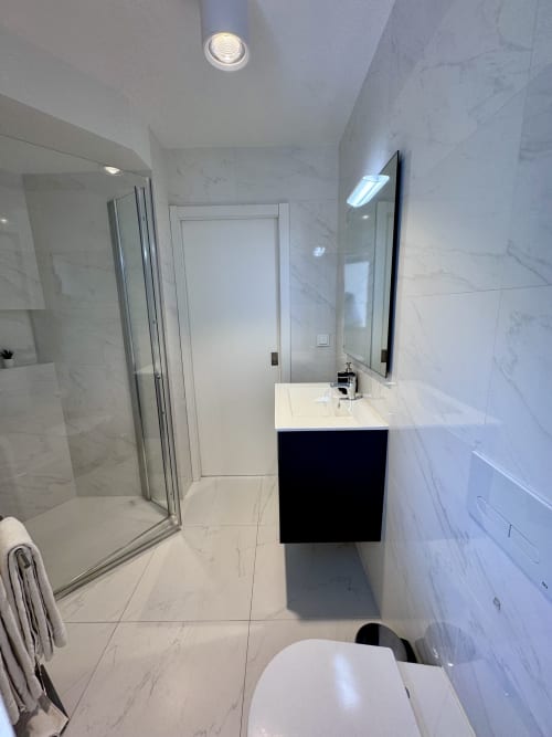 Modern bathroom in RIA CENTRUM Deluxe Black & White room, Aveiro, with marble tiling, black vanity, mirror and shower