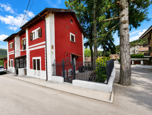 Luminosa villa alpina rosso e bianca con vista montagna a Ovindoli. Villa indipendente con patio recintato e alti pini