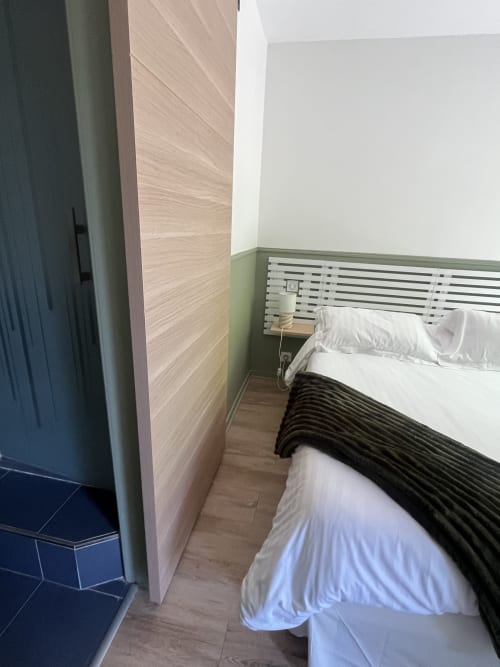 Chambre moderne à L'Auberge de la Pointe à Soustons avec lit, tête de lit rayée, parquet et mur d'accent vert