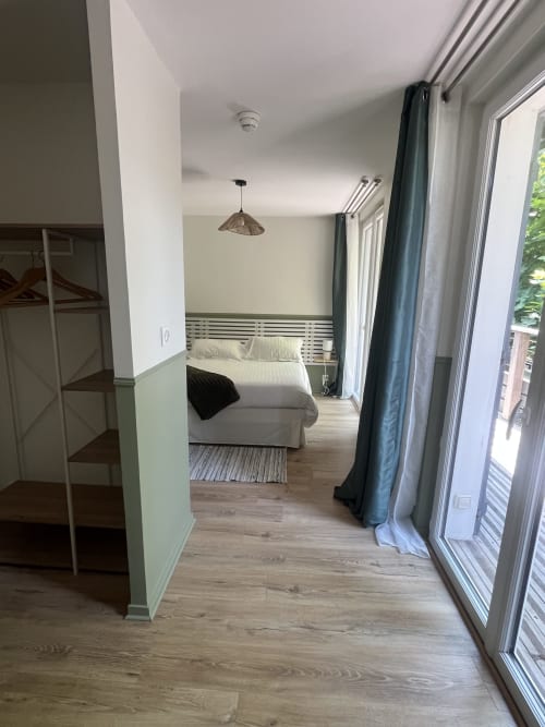 Chambre d'hôtel moderne à L'Auberge de la Pointe avec vue sur le lac, lit, portes coulissantes vers le balcon et mobilier contemporain
