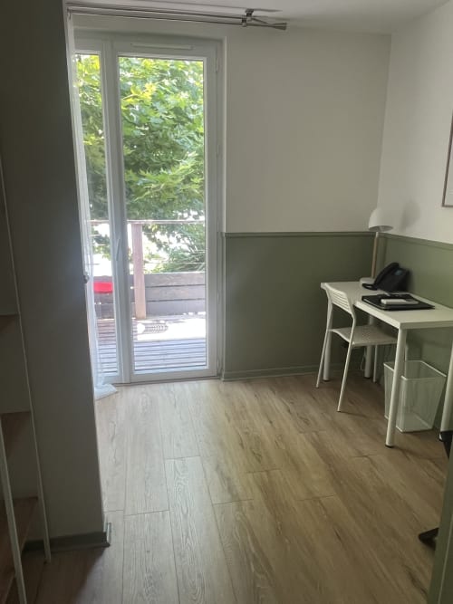 Chambre moderne de L'Auberge de la Pointe à Soustons avec portes-fenêtres, mur vert, bureau et vue sur le lac
