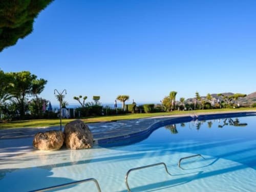 Piscina de lujo en Nerja Holiday Homes con vista al mar, tumbonas, jardines cuidados y paisaje mediterráneo