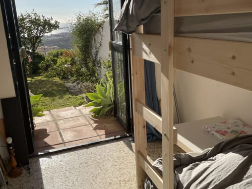 Dormitorio con cama litera de madera que se abre a una terraza ajardinada con vistas al mar en el apartamento de lujo Nerja Holiday Homes en España