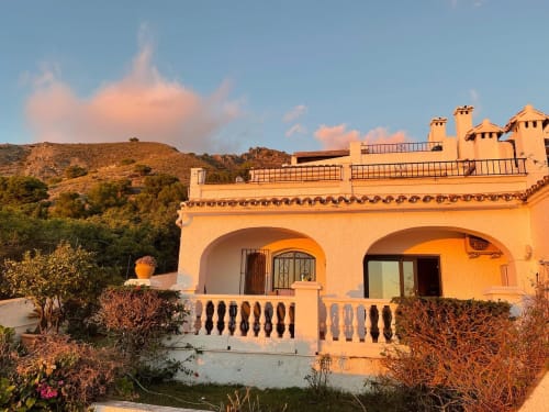 Villa mediterránea naranja con arcos en Nerja, España, con terraza y vistas a la ladera al atardecer