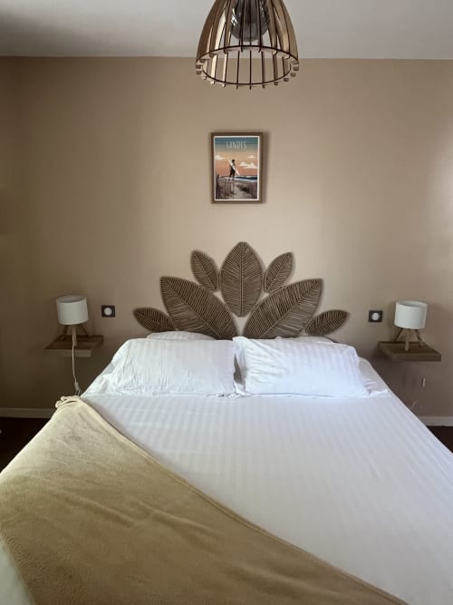 Chambre moderne à L'Auberge de la Pointe avec tête de lit en feuilles tressées, literie blanche et décoration murale vue sur le lac à Soustons.
