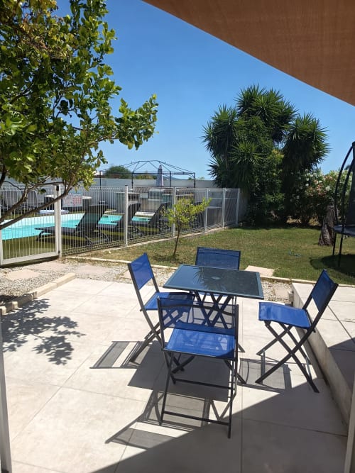 Outdoor patio with blue dining set overlooking pool at Pugetvilla cottage in Puget-Ville, France