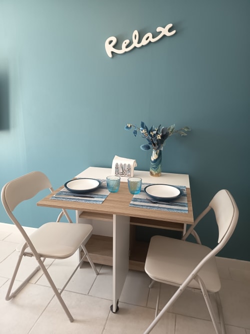 Peaceful dining setup at Pugetvilla cottage with 'Relax' neon sign, wooden table, blue accents, and cream chairs in
