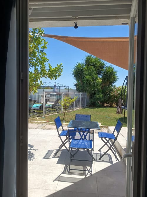 Sunny patio with blue chairs and table at Pugetvilla cottage, overlooking pool and waterfront garden
