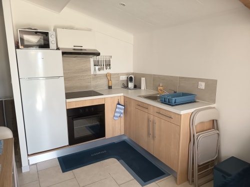 Compact kitchen in Gîte Mer cottage at Pugetvilla, Puget-Ville with white appliances and wooden cabinetry