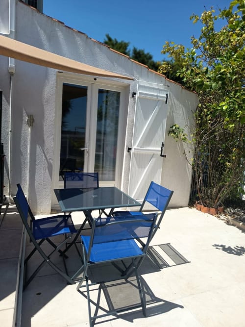 Cottage patio at Pugetvilla with blue chairs, table, and white exterior in Puget-Ville