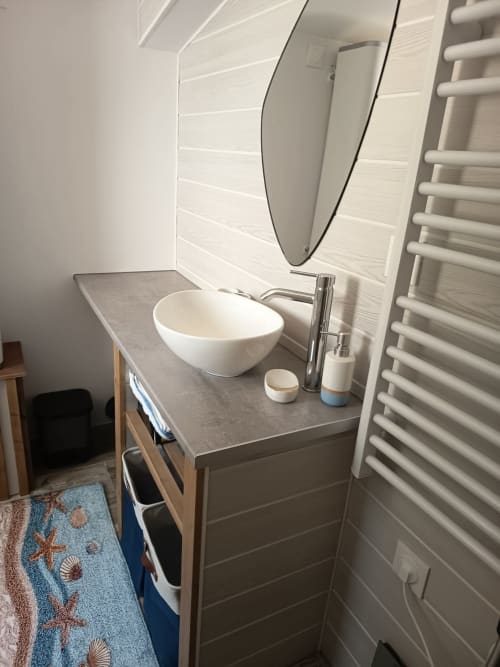 Modern bathroom vanity at Pugetvilla cottage with round white sink, mirror, and heated towel rack