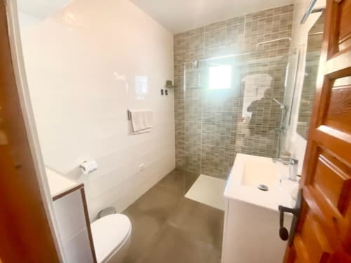 Baño moderno con ducha abierta, lavabo e inodoro en lujoso apartamento de Nerja Holiday Homes en España
