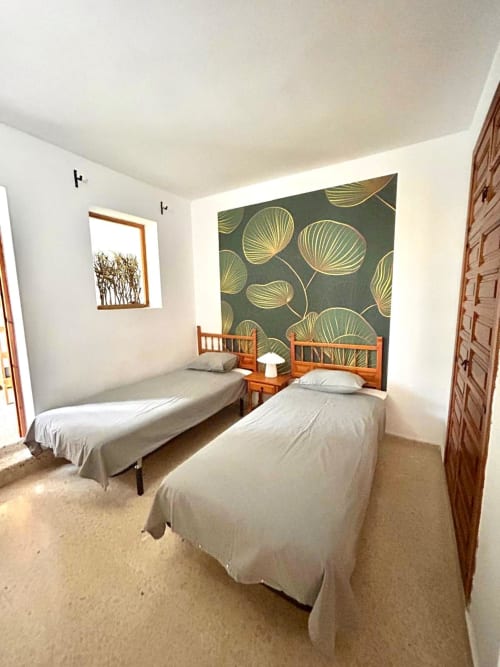 Dormitorio doble en apartamento de lujo de 3 habitaciones en Nerja Holiday Homes con camas de madera, arte botánico en paredes y comodidades modernas