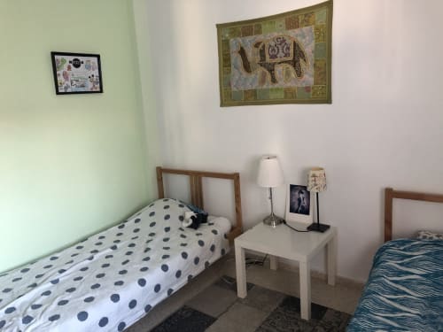 Dormitorio compartido en apartamento familiar de Nerja con dos camas, mesita de noche, lámpara y cuadros decorativos