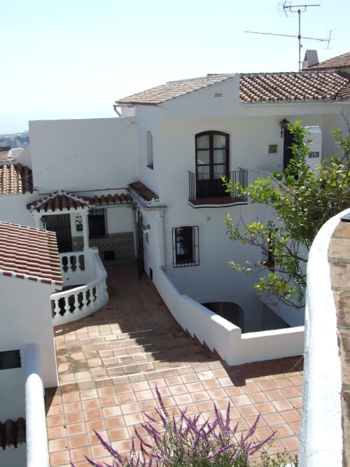 Apartamento mediterráneo blanco en Nerja con patio de azulejos de barro, plantas verdes y arquitectura española tradicional