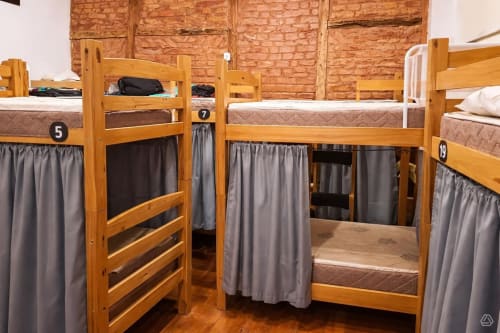 Dormitório misto com beliches de madeira numerados 5, 7 e 19 na Rio Vibes Hostel no Rio de Janeiro, com cortinas