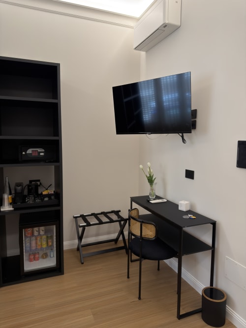 Camera moderna di Maison Riviera con TV a parete, scrivania nera, minibar e arredi contemporanei a Reggio di