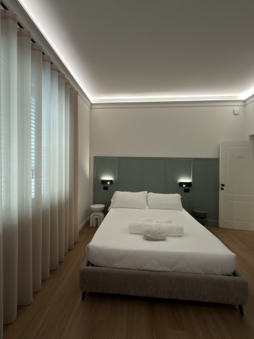Camera moderna a Maison Riviera a Reggio di Calabria con letto matrimoniale, testata verde, biancheria bianca, finestre a tutta altezza