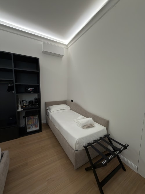 Camera moderna a Maison Riviera con letto gemello, soffitto LED, scaffale nero, minibar e pavimento in legno a Reggio di