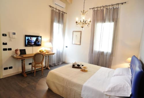 Camera elegante alla Finestra sul porto di Cesenatico con letto, scrivania, TV, lampadario e finestre con tende