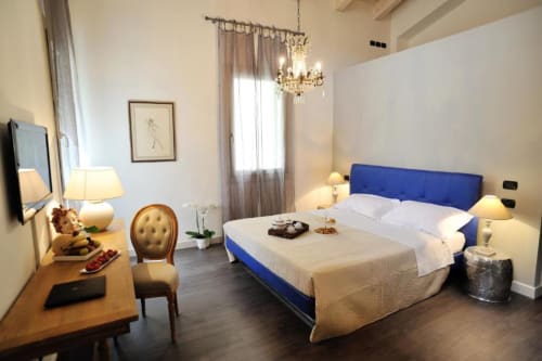 Elegante camera da letto a La Finestra sul porto di Cesenatico con letto imbottito blu, scrivania in legno, lampadario e arredi moderni