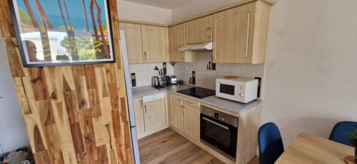 Cuisine avec meubles en bois clair, cuisinière noire, micro-ondes et table à manger dans l'appartement O SOLEIL aux Terrasses des Lecques