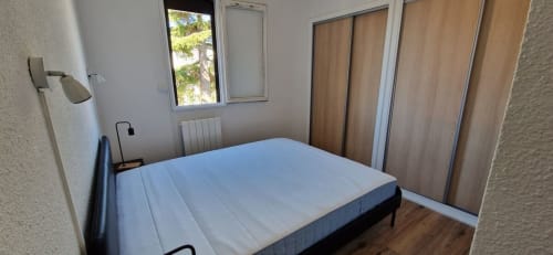 Chambre avec lit double, armoire en bois, fenêtre avec vue sur le jardin de l'appartement Terrasses des Lecques près de la plage