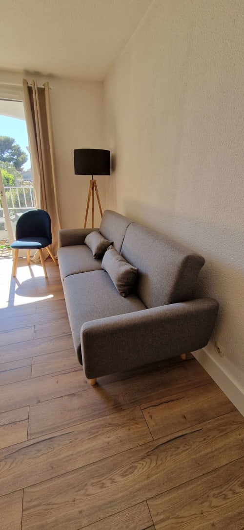 Séjour moderne avec canapé gris, parquet et lampadaire à l'Appartement O SOLEIL à Saint-Cyr-sur-Mer