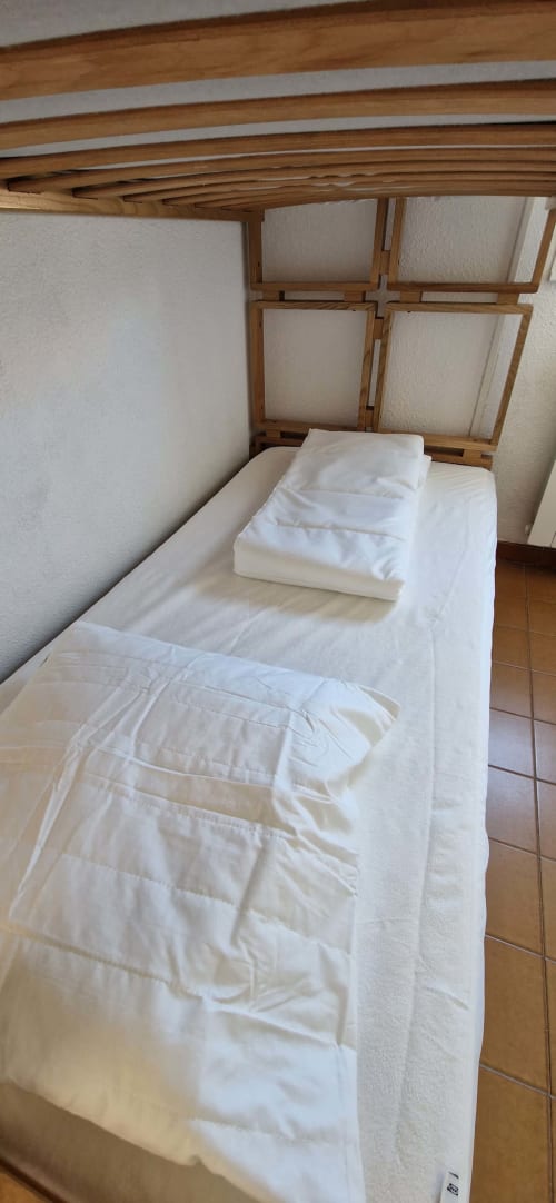 Chambre douillette de l'appartement O SOLEIL aux Terrasses des Lecques avec literie blanche, poutres en bois et vue sur le jardin