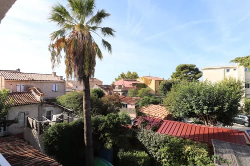 Vue du jardin des Terrasses des Lecques à Saint-Cyr-sur-Mer avec palmier et toitures de villas méditerranéennes
