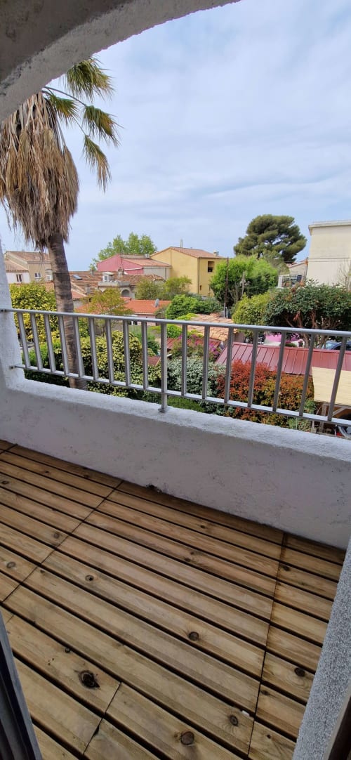 Vue depuis le balcon du village de Saint-Cyr-sur-Mer avec maisons colorées, palmier et jardin méditerranéen aux Terrasses des Lecques