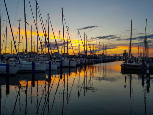 Barche a vela ormeggiate al porto di Cesenatico al tramonto, riflessi di luce dorata nelle acque tranquille