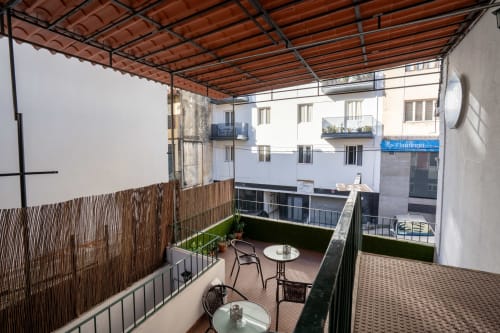 Terraço do hotel Madeirarooms em Funchal com área coberta, plantas em vasos e vista da cidade