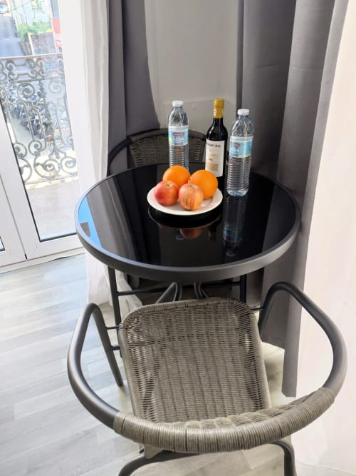 Mesa redonda preta com garrafas de água, vinho e frutas frescas no quarto do hotel Madeirarooms, Funchal com vista de varanda