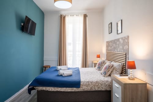Quarto de casal moderno na Madeirarooms Funchal com parede azul-petróleo, varanda, TV e móveis contemporâneos