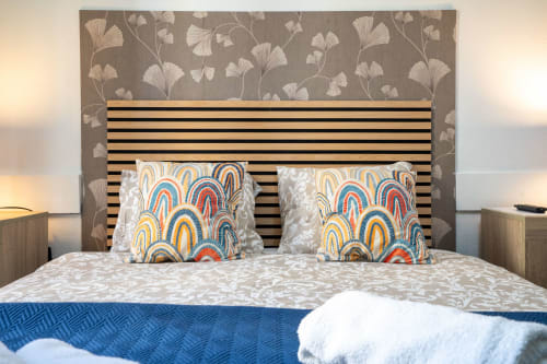 Quarto de casal moderno em Madeirarooms Funchal com cabeceira às riscas e almofadas com estampados coloridos