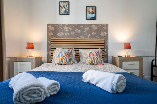 Quarto duplo moderno no hotel Madeirarooms em Funchal com roupa de cama azul, cabeceira listrada, almofadas estampadas e vista da cidade