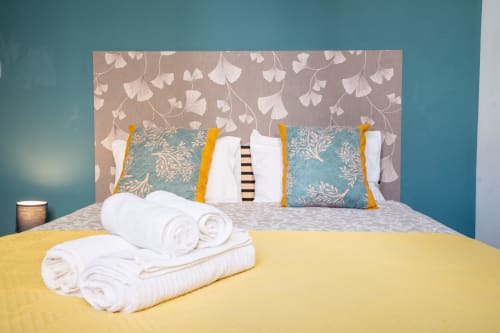 Quarto duplo moderno na Madeirarooms Funchal com parede de destaque turquesa, cabeceira decorativa e toalhas brancas enroladas