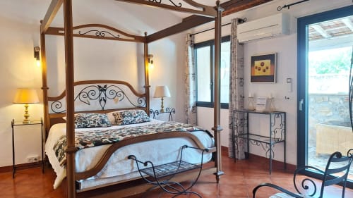 Chambre de lune de miel élégante à La Bergerie Du Moulin avec lit à baldaquin, décor en fer forgé et carrelage en terre cuite