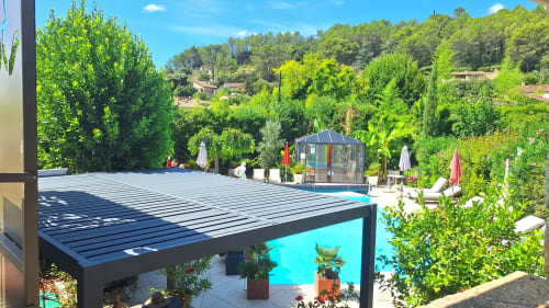 Espace piscine de La Bergerie Du Moulin avec pergola moderne, piscine turquoise et jardins luxuriants à Taradeau, France