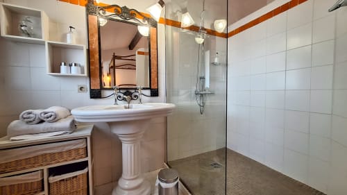 Salle de bains élégante à La Bergerie Du Moulin avec lavabo sur piédestal, douche vitrée et accents bois