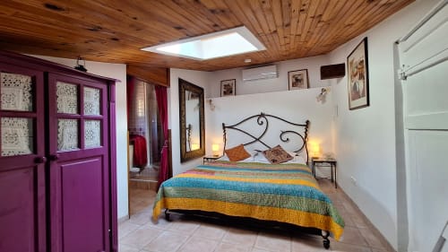 Chambre douillette à La Bergerie Du Moulin B&B à Taradeau avec literie rayée colorée, lit en fer forgé, plafond en bois